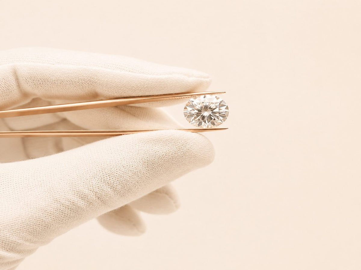 Diamant de synthèse rond tenu à la pince par une main gantée de blanc