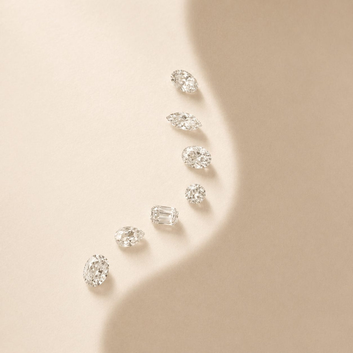 Diamants naturels taillés disposés en courbe sur un fond beige, entre ombre et lumière