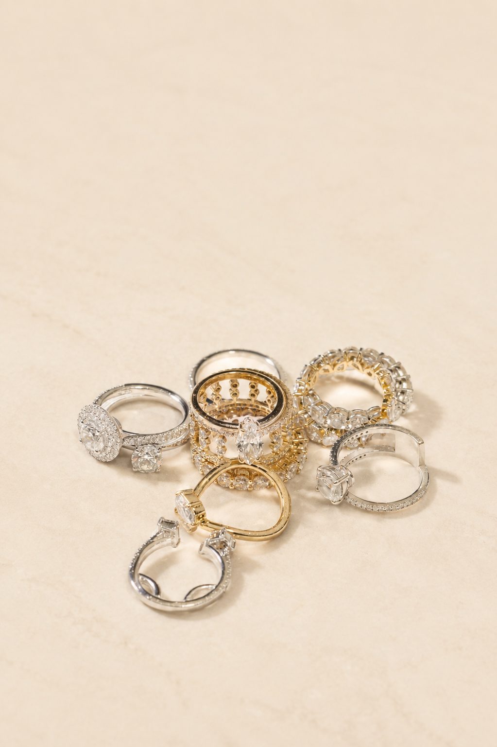 Bagues en diamants de différentes formes, en or jaune et or blanc, posées sur une pierre beige