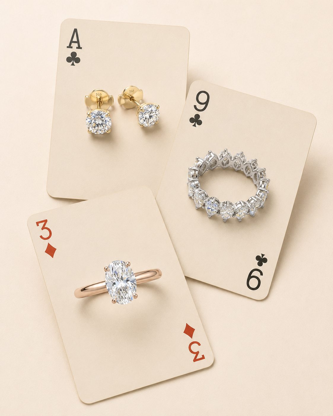 Puces d'oreilles, alliance tour complet et bague ovale en diamants posées sur des cartes à jouer