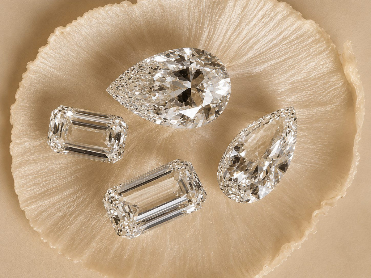 Quatre diamants taille poire et taille émeraude posés sur une étoffe de soie beige