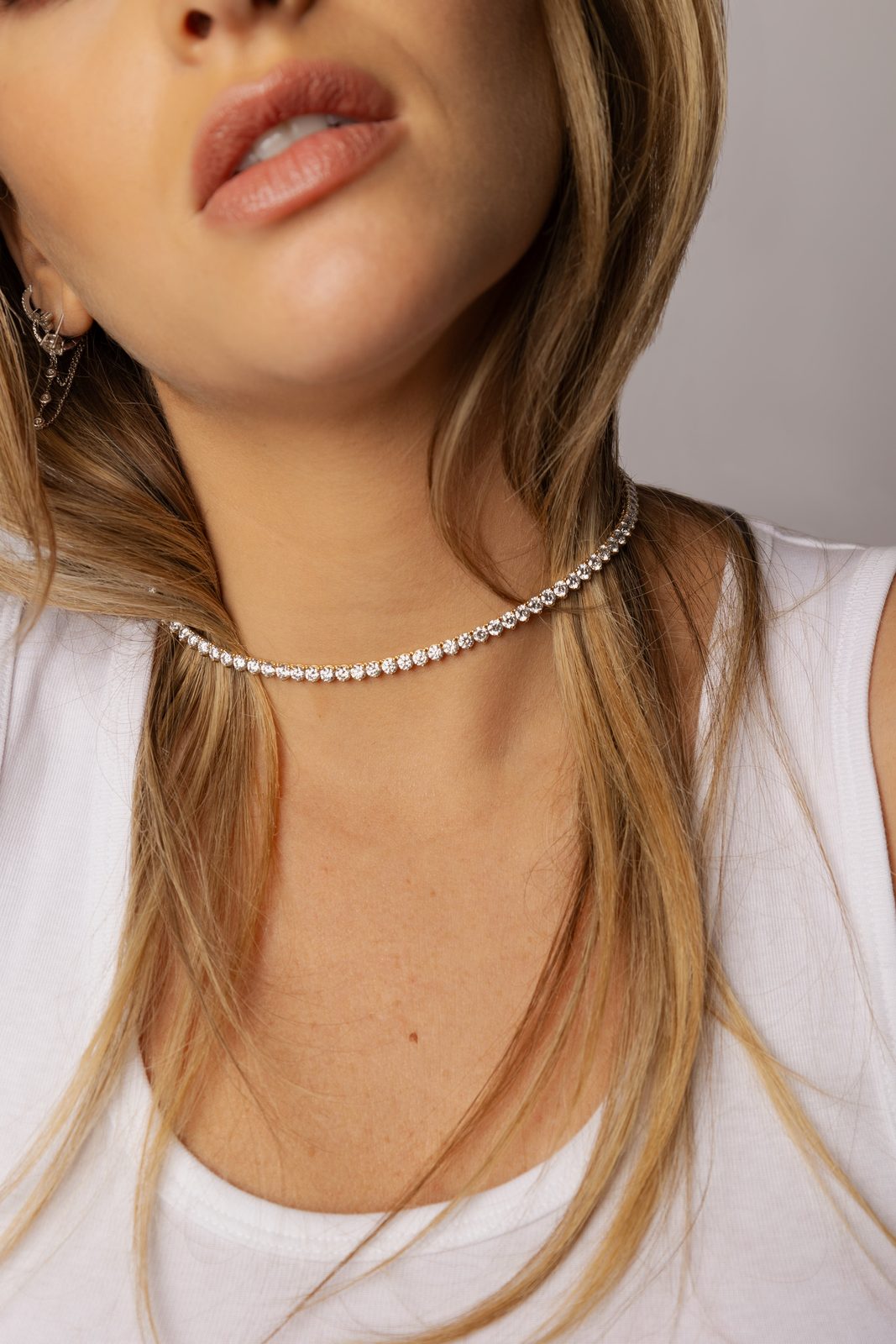 Collier rivière de diamants porté sur un top blanc par une femme aux cheveux blonds, création Noely Diamant