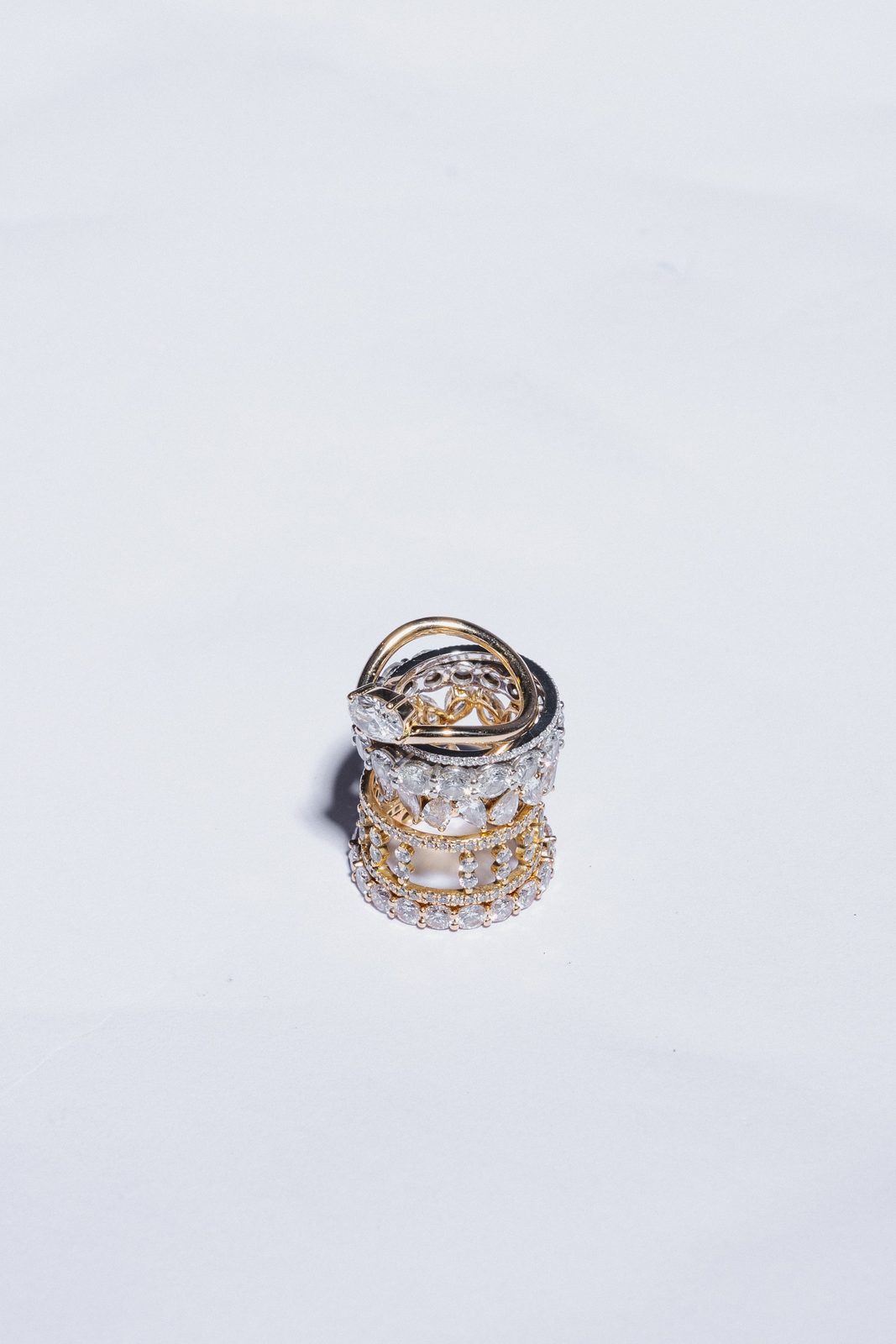 Empilement de bagues en or et diamants posé sur un fond blanc